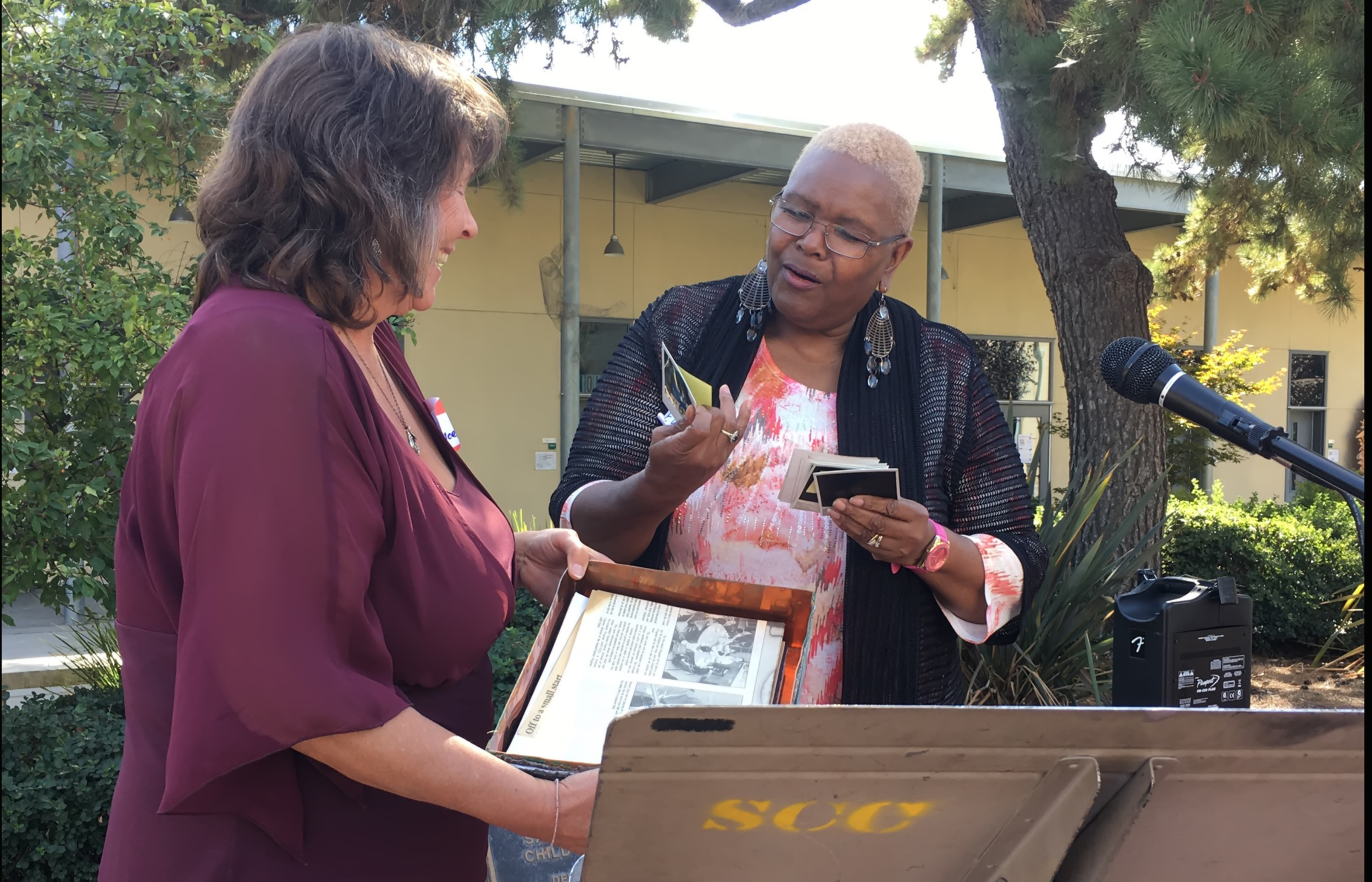 Luretta Bruce (R) and Eunice Graves (L) show pictures from the Child Development Center Time Capsule buried in 1993, the time capsule was opened at City College on Oct. 7. The center was the first childcare center on a community college campus in the state. Photo by Zachary FR Anderson