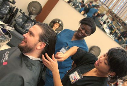 City College professor Craig Davis gets his haircut Feb. 27 by cosmetology student Thu Vo assisted by Troia Sheard during the promotional food drive to bring in a canned food and get a free haircut event. Photo by Windee Dawson.