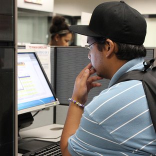 A male student is reading a computer screen.