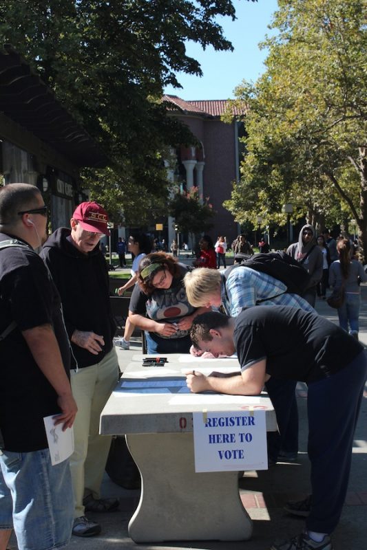 Bill Maham, an ex-history teacher from City College who comes back every 4 years for voter registration, helps Anthropology majors Nikole Gates and Dylan Cann, and Administration of Justice major Andrew Martinez, sign up to vote for this year's election. Jason Van Sandt | jasonv1977@gmail.com