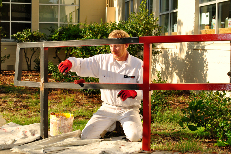 A man painting a handrail outside.