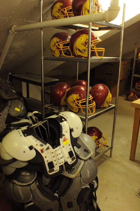 Football helmets and shoulder pads located in a storeroom.