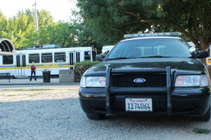 Police car sits in front of passing Regional Transit Light Rail train. 