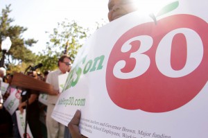 A student holding a sign that says Yes on Prop 30