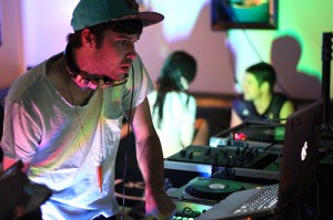 A male Deejaying at a set of turntables.