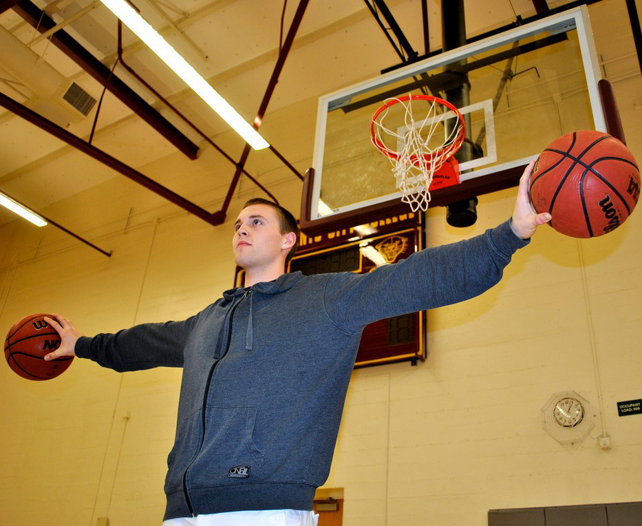 Jordan Coen-Kotecki holding two basketballs on the City College court. 