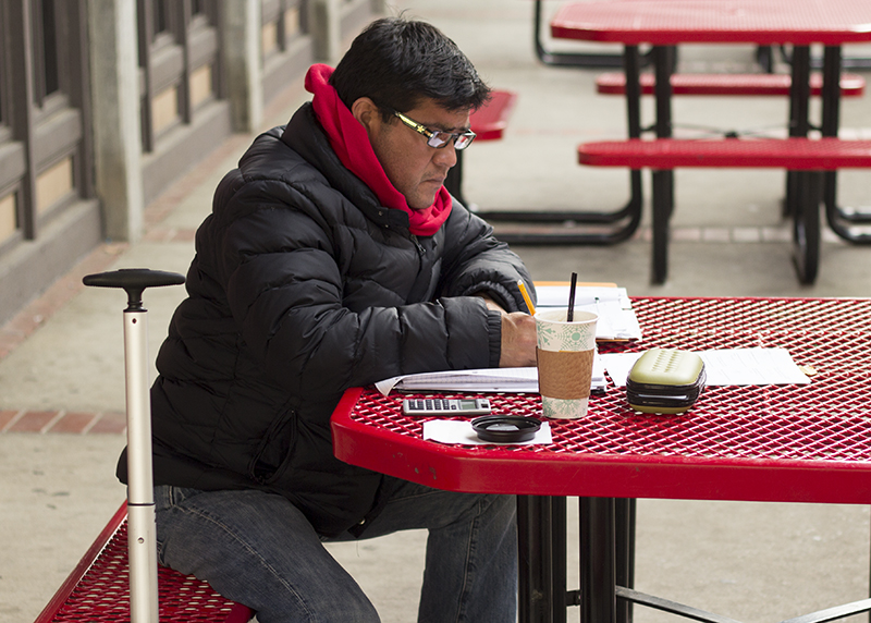 A male student studies at a bench in the quad.