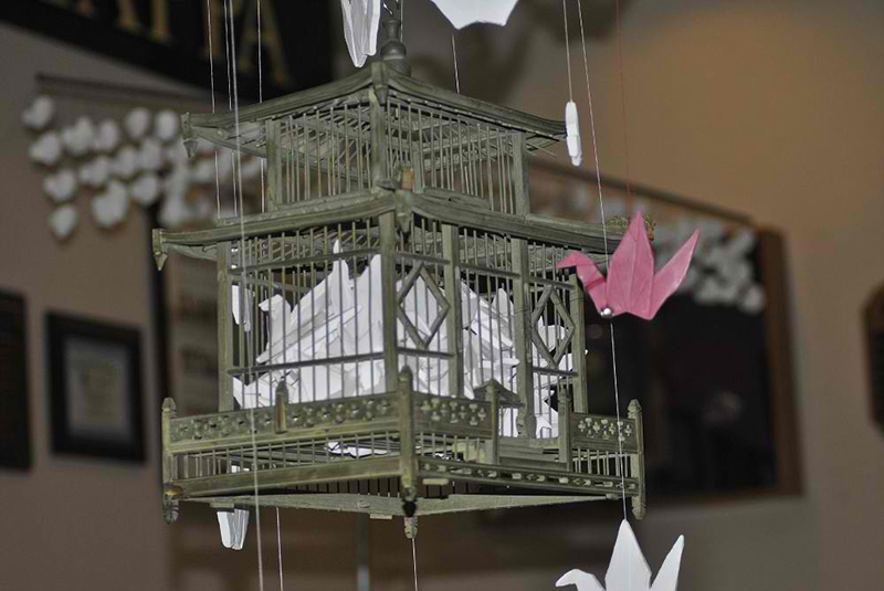 A bird house filled with origami cranes.