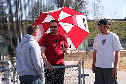 PICTURE OF THE DAY – 2/27/13 John Badovinac, assistant track coach for throws, holds his favorite umbrella for keeping out of the sun while discussing throwing techniques with former student athlete Trent Roberts and currrent student Garett Siscel, 20, Social Science major. | Kelvin Sanders Sr. | ksanderssrexpress@gmail.com