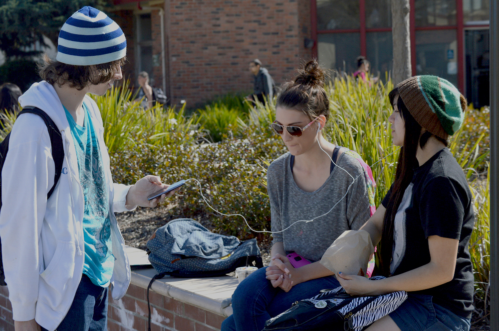 City College student William Ruygt (left)  uses his cell phone Feb. 24 to share music he created on SoundCloud (qAke) with fellow student-friends Allison Lowe and Vanessa Escobar along the walkway across from Lusk Aeronautics Center. Luisa Morco | Staff Photographer | luisamorco.express@gmail.com