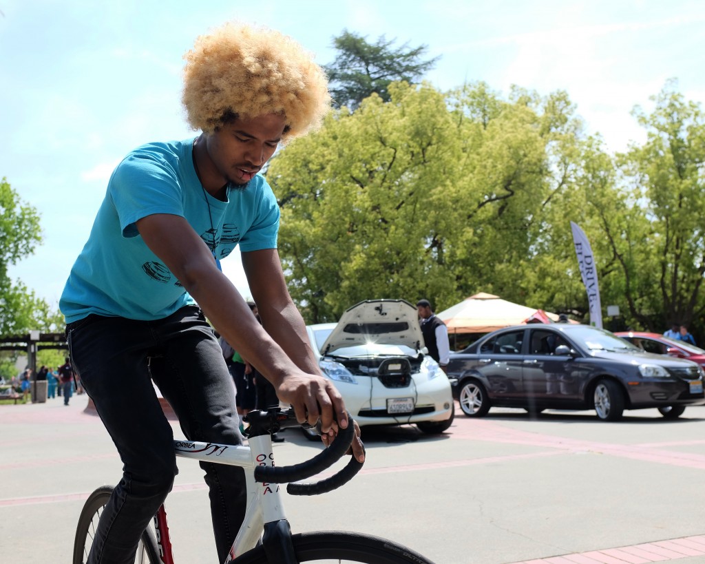 City College mechanical engineering student Isaias Iglesias, riding his bike through campus. Electrical cars are displayed for Earth week in front of the Performing Arts Center April 21, 2015. Vhonn Ryan Encarnacion | Staff Photographer | ryanvhonn@gmail.com