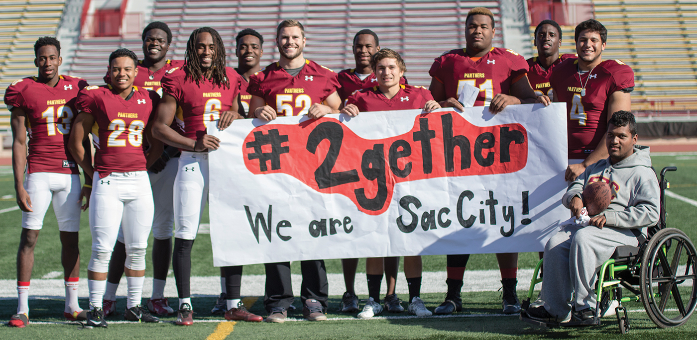 Some City College football players stand with Anthony with a sign signaling mental health awareness.