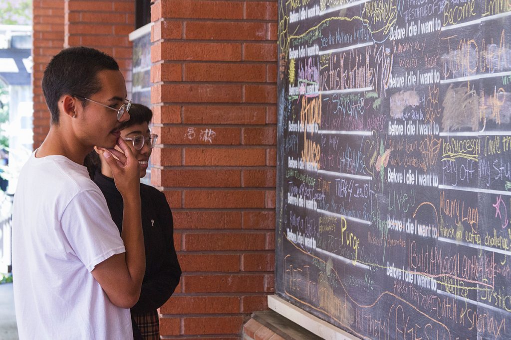 City College fashion student, Jaidyn Cobbs, and friend Eli Prince look upon the Before I Die Projects blackboard wall in front of the City Café. 

Katelyn Stark. | katelynstarkexpress@gmail.com | Staff Photographer
