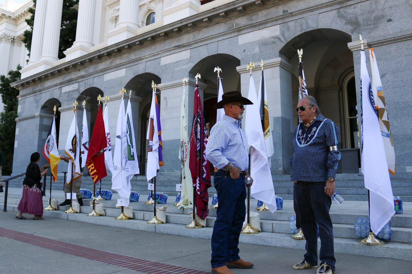 Dave Toler (left), a San Pasqual reservation counselor talks with Bill Gollnick, a tribal administrator for the Tejon tribe, at the 2016 Native American Day event. Behind them, flags of California tribes placed on the west steps of the State Capitol. Sept. 23, 2016. Corey Browning | Staff Photographer | coreybrowningexpress@gmail.com