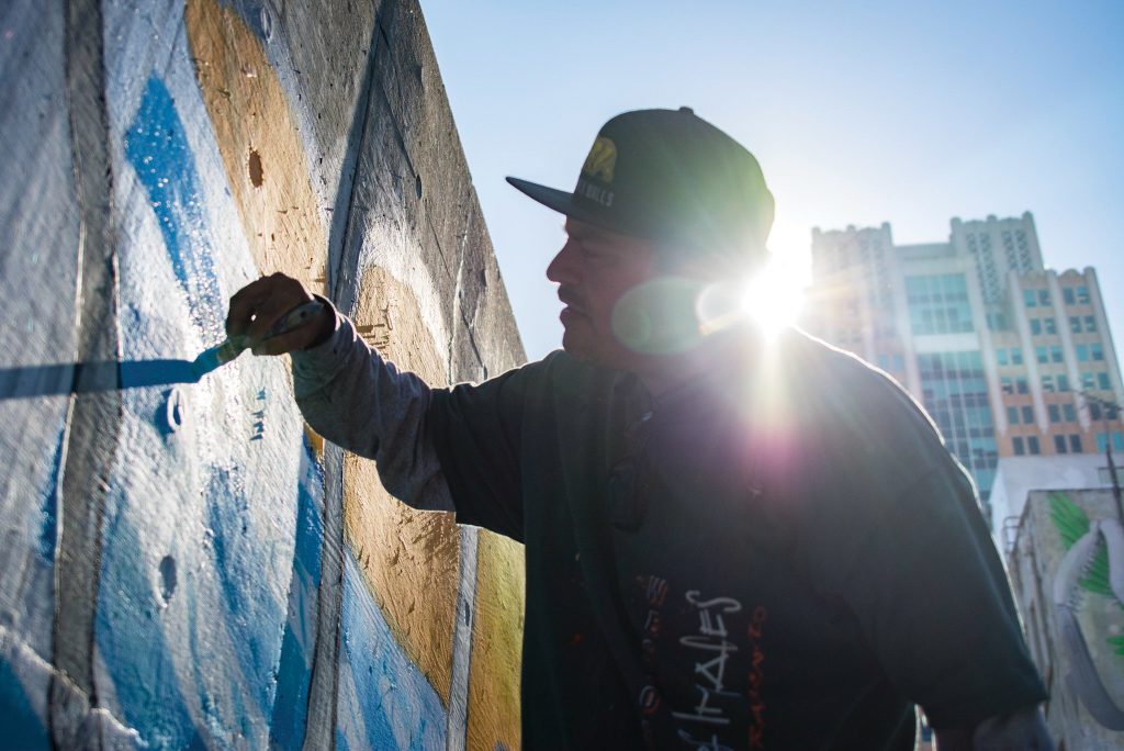 Markos Egure works on the Humanity mural Aug. 28, a work made by the ARTners Collaborative. The mural is located on Improv Alley between 7th and 8th streets. Jason Pierce | Photo Editor | jpierce.express@gmail.com