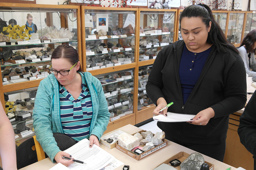 Geology major, Sonia Miller (left) assists lab partner, Priscilla Viveros in identifying rock and mineral specimens during a lab exercise Thursday, Feb. 1. Miller works for the California Department of Water Resources and is earning her master's degree. | Photo by Nita Gardipee | Staff Reporter | ngardipee.express@gmail.com
