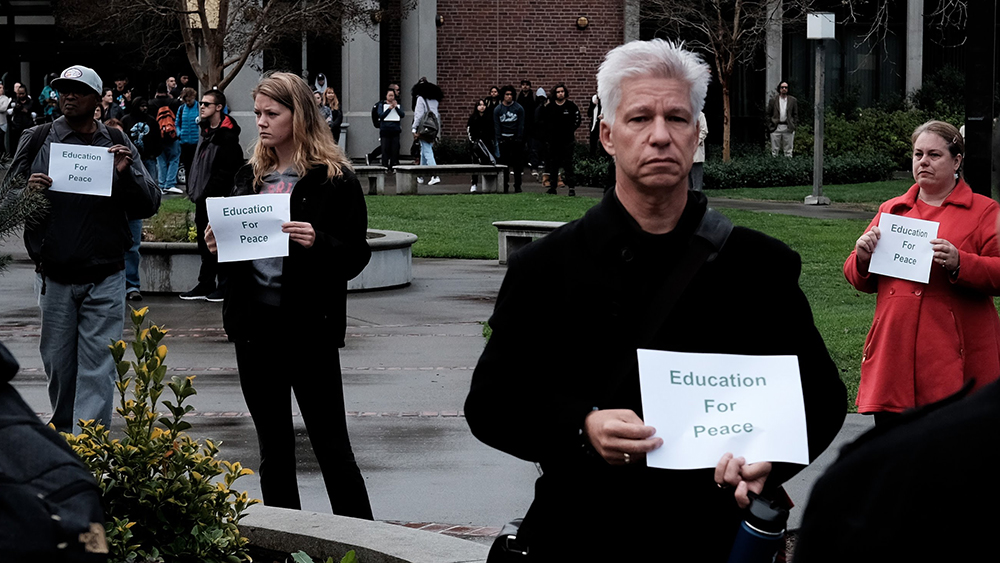 Norman Lorenz, staff resource center coordinator, along with City College students and faculty gather in the quad  to participate in the national walkout to honor the high school shooting in Parkland, Florida last month. Phoenix Kanada | Staff Photographer | pkanada.express@gmail.com
