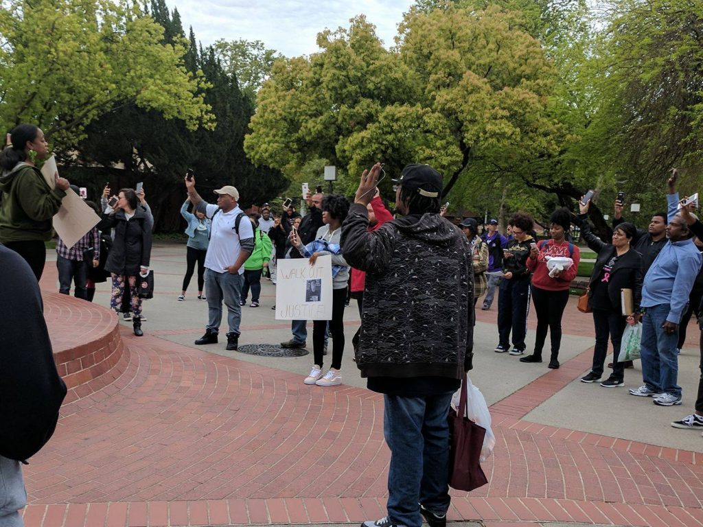 From the fountain by the Performing Arts Center, Kandra Coleman addresses the participants of an unofficial walkout as they hold their phones up in solidarity with Stephon Clark April 18. Photo by Heather Roegiers | Editor-in-Chief | kroegiers.express@gmail.com