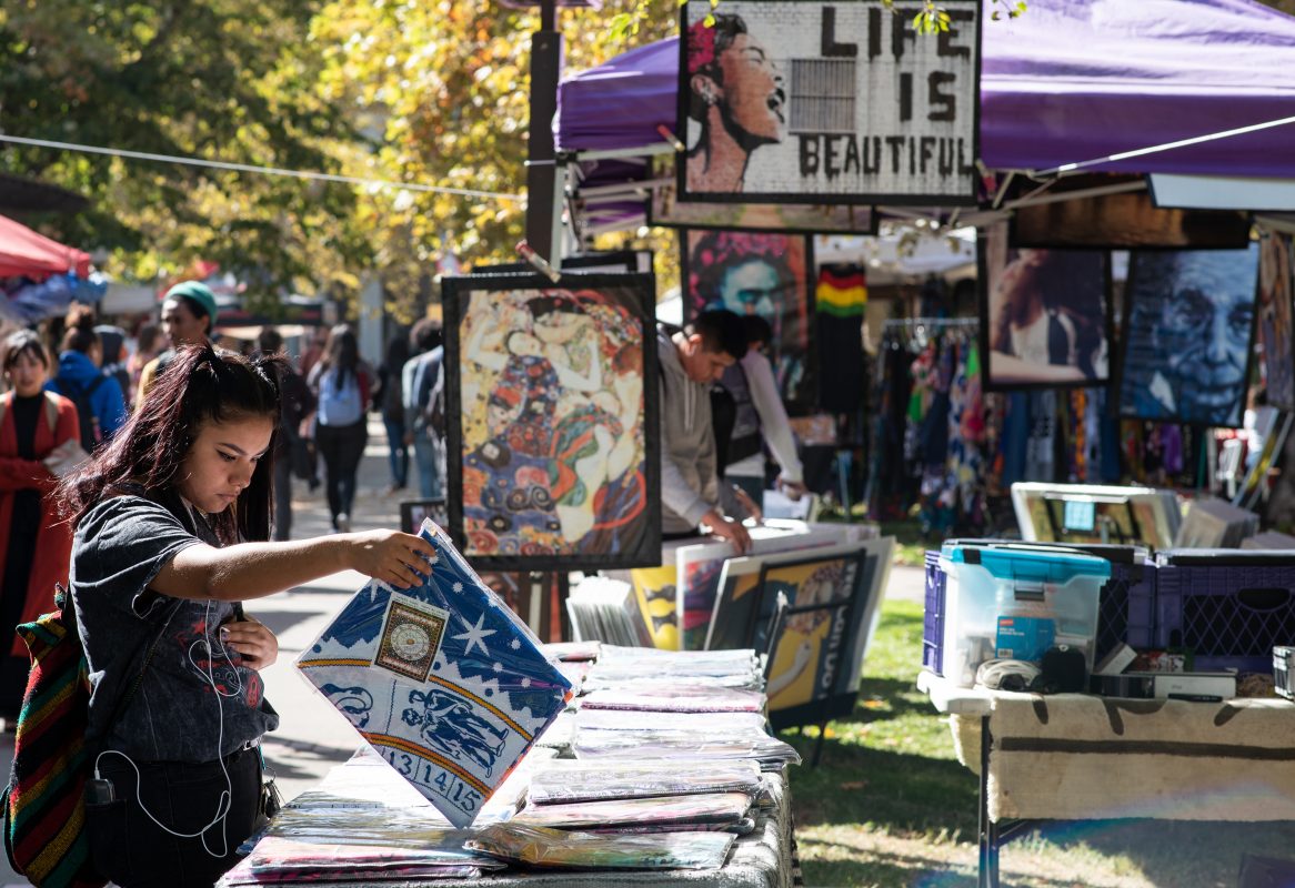Jennifer Casillas, English and psychology majors, checking the tapestries at the poster stand during the Art and Craft Fair and Wellness Festival in the Quad at City College Wednesday, Oct. 9 2019. (Marco Uceda/makos.uceda11@gmail.com)