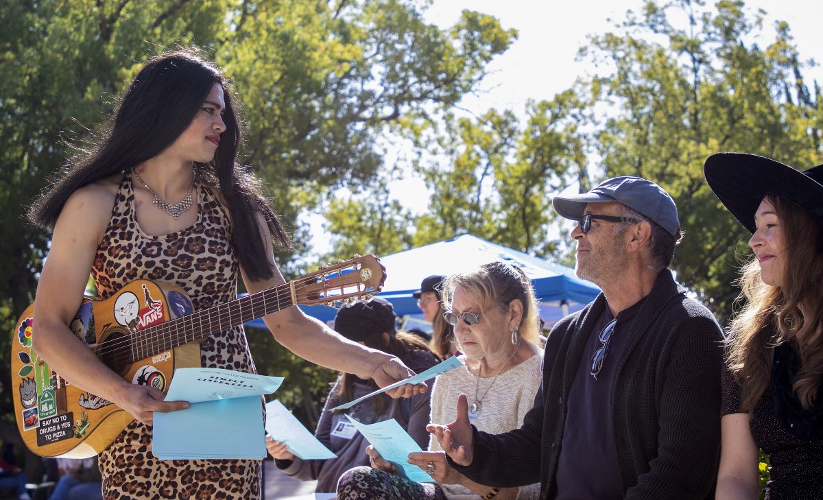 Vincent Barnett, theater major, hands a flyer for the “Simply Cinderella” play to Craig Stice, father of singer Tara Stice (right), during the Commercial Music Ensemble’s Halloween concert in the quad at City College Thursday, Oct. 31, 2019.
 (Sara Nevis/snevis.express@gmail.com)