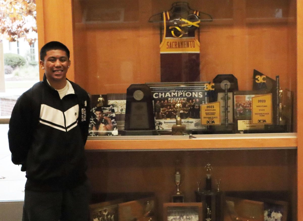 Sacramento City College’s men’s wrestling team captain, Ben Quilpa, stands next to the trophy display inside City College’s North Gymnasium, Wednesday, Nov. 20, 2024, in Sacramento, Calif. 
