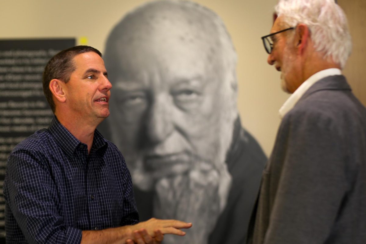 Sacramento City College Dean Paul Estabrook attends the reception for the Coastal Photography Exhibition at the Russ Solomon Gallery at Sacramento City College on Wednesday, Oct 30. 2025 in Sacramento, Calif. Estabrook is in front of  the Russ Solomon Portrait taken by Sacramento City College Professor Randy Allen. 